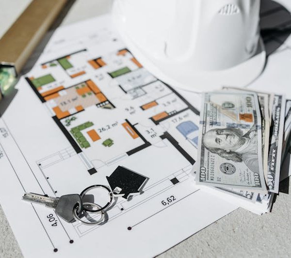 a home plan, house keys, a leveling tool, and some cash